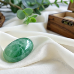 Polished green jadeite (Jadeitový Kameň) on a soft fabric.
